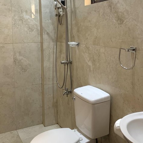 Ein modernes Badezimmer mit einer Dusche, komfortablem WC und eleganter Steinfliesen. Helle Beleuchtung sorgt für eine freundliche Atmosphäre.