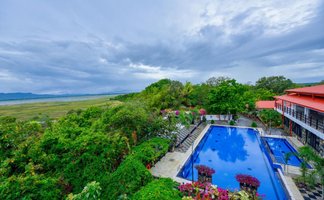 Ein atemberaubender Blick auf einen blauen Pool, umgeben von üppigem Grün und bunten Blumen in einer ruhigen Landschaft.