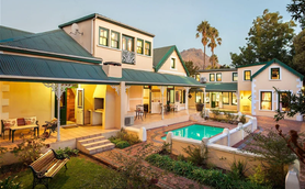 Ein elegantes, zweigeschossiges Haus mit grünem Dach, umgeben von einem gepflegten Garten und einem einladenden Pool.