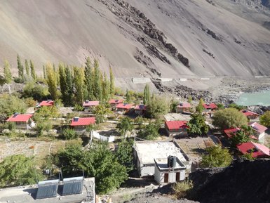 Eine malerische Ansicht eines kleinen Dorfes am Himalaya, umgeben von hohen Bergen und üppiger Vegetation.