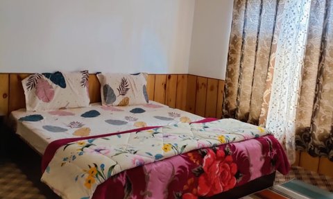 Ein gemütliches Schlafzimmer mit einem großen Bett, bunten Decken und einem Fenster mit dekorativen Vorhängen.