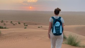 Frau läuft in der Wahiba-Wüste beim Sonnenuntergang – Oman Reise mit Kindern