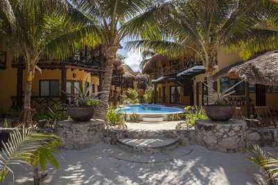 Ein einladender Pool umgeben von Palmen und bunten Gebäuden, ideal für entspannende Tage am Strand.