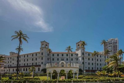 Das Hotel Caribe strahlt mit seiner weißen Fassade und den Palmen im Vordergrund eine einladende Atmosphäre aus.
