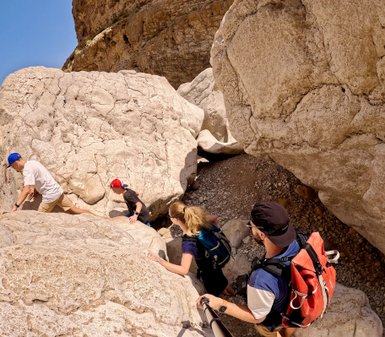 Familie spaziert zwischen Felsen im Wadi Bani Khalid im Oman – Oman Familienreise