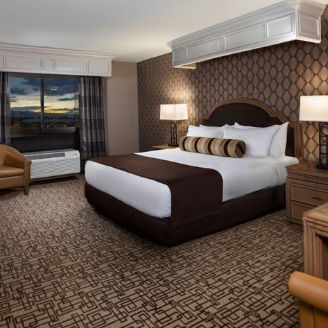 Ein elegantes Hotelzimmer mit einem großen Bett, einem gemütlichen Sessel und einem Fenster, das einen Blick auf die Stadt bietet.