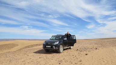 Mädchen fährt im Jeep durch die weiten Sandlandschaften der Sahara – Marokko Reise mit Kindern