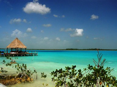 Holzüberdachte Hütte am langen Steg über türkisfarbenem Wasser – Mexiko Reise mit Kindern
