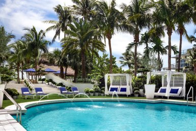 Ein einladender Poolbereich in Miami Beach, umgeben von Palmen und modernen Liegen, ideal für Entspannung und Erholung.