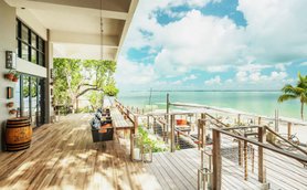 Eine großzügige Terrasse mit Holzbohlen bietet einen herrlichen Blick auf das glitzernde Wasser und den blauen Himmel.