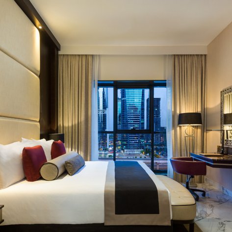 Ein elegantes Hotelzimmer mit einem großen Fenster, das einen Blick auf moderne Wolkenkratzer bietet.