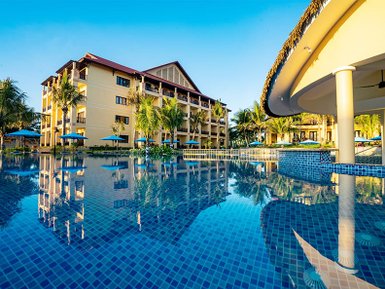 Ein luxuriöser Pool spiegelt die Farben des Himmels wider, umgeben von Palmen und einem eleganten Resortgebäude.