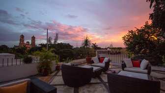 Eine gemütliche Terrasse mit modernen Möbeln bietet einen atemberaubenden Blick auf die bunten Wolken des Sonnenuntergangs.