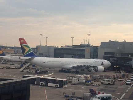 Ein großer Passagierflugzeug der South African Airways steht am Flughafen, umgeben von Gepäck und anderen Fahrzeugen.