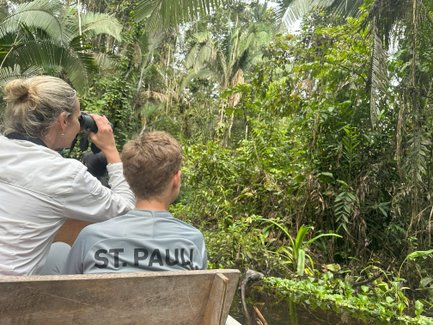 Eine Frau beobachtet mit einem Fernglas die üppige Vegetation des Dschungels, während ein Junge aufmerksam zuschaut.
