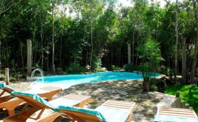 Ein einladender Pool umgeben von üppigem Grün, mit Liegen aus Holz und blauen Handtüchern für entspannende Stunden.