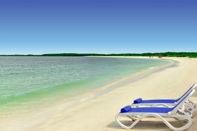 Ein ruhiger Strand mit sanften Wellen, weißen Sand und blauen Liegen, die zum Entspannen einladen.