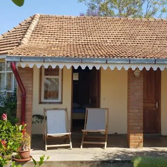 Ein gemütlicher Bungalow mit einem roten Ziegeldach, umgeben von üppigem Grün und blühenden Pflanzen.