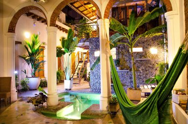 Ein einladender Innenhof mit einem kleinen Pool, umgeben von tropischen Pflanzen und einer gemütlichen Hängematte.