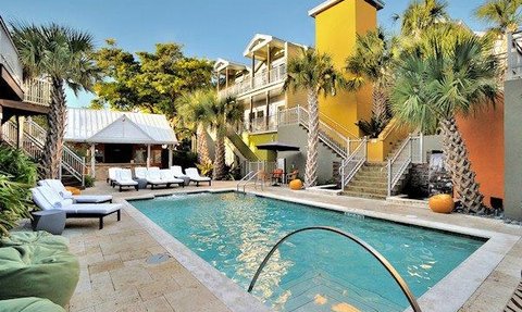 Ein einladender Poolbereich mit Liegen, umgeben von Palmen und bunten Gebäuden in Florida, ideal für Entspannung.