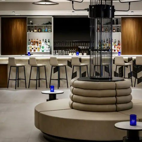 Ein eleganter Hotelbarbereich mit einer stilvollen Theke, umgeben von modernen Stühlen und einer gemütlichen Sitzgelegenheit.