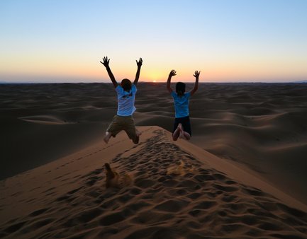 Kinder genießen den Sonnenuntergang in den Sanddünen der Sahara – Familienreise nach Marokko
