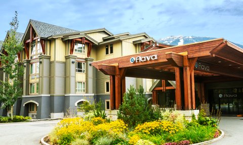 Das Aava Hotel in Whistler zeigt eine moderne Architektur mit Holzverkleidung und großen Fenstern, umgeben von bunten Blumen.