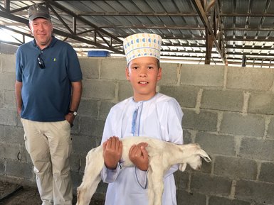 Kind hält eine Ziege auf einem Bauernhof im Oman – Oman Reise mit Kindern