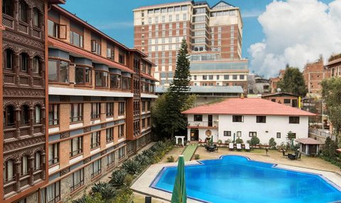 Ein einladender Pool umgeben von gepflegten Gärten und modernen Gebäuden, ideal für Familienurlaube in Nepal.