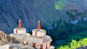 Zwei historische Stupas stehen vor einem majestätischen Tal