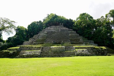 Die beeindruckenden Lamanai-Ruinen zeigen eine große, stufenförmige Pyramide, umgeben von üppigem Grün und Bäumen.