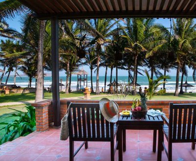 Ein einladender Veranda-Bereich mit Blick auf das Meer, umgeben von Palmen und einer entspannten Atmosphäre.
