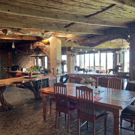 Ein einladendes Restaurant mit rustikalem Holzdekor, großen Fenstern und einem Blick auf die Natur draußen.