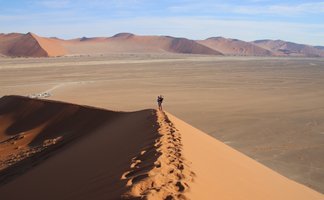 Eine Mutter steht mit ihrem Kind auf dem Arm auf einer Düne - Namibia Reise mit Kindern