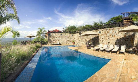 Ein einladender Poolbereich mit Liegen und Sonnenschirmen, umgeben von üppigem Grün und einer beeindruckenden Aussicht.