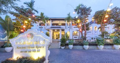 Das Ancient House Resort in Hoi An zeigt eine elegante Fassade mit bunten Laternen und üppiger Vegetation im Vordergrund.