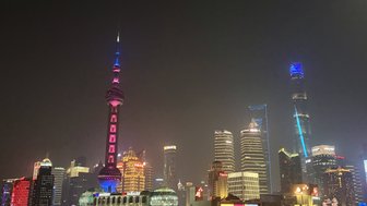Die beeindruckende Skyline von Shanghai erstrahlt nachts in bunten Lichtern, mit dem ikonischen Oriental Pearl Tower im Vordergrund.