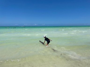 Junge spielt im klaren Wasser vor der Küste von Holbox – Mexiko mit Kindern
