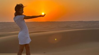 Mädchen hält die Sonne beim Sonnenuntergang in der Wüste Omans fürs Foto – Oman Familienreise