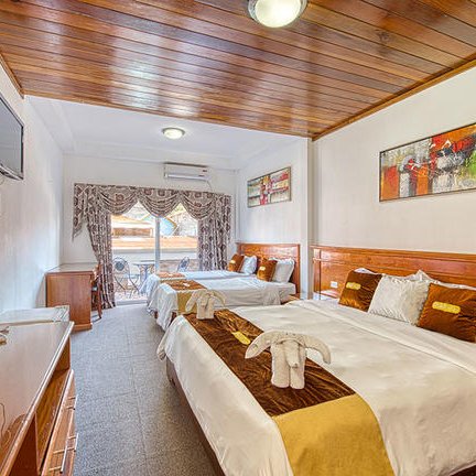 Ein helles Hotelzimmer mit zwei Betten, eleganter Holzdecke und einem großen Fenster, das auf einen Balkon führt.