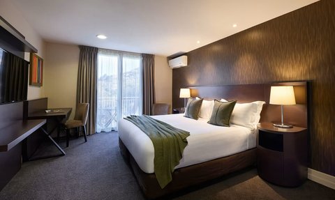 Ein elegantes Hotelzimmer mit einem großen Bett, dekoriert mit Kissen und einer warmen Decke, bietet eine gemütliche Atmosphäre.