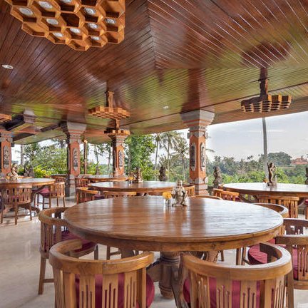 Ein eleganter Essbereich mit runden Holztischen und Stühlen, umgeben von einer malerischen Landschaft in Bali.
