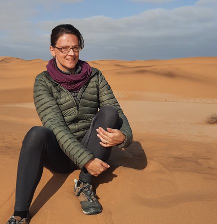 Eine Frau sitzt auf einer Düne in der Wüste - Namibia Reise mit Kindern