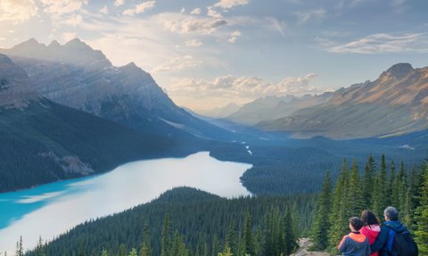 Ein Paar und ein Kind stehen auf einem Aussichtspunkt und bewundern die atemberaubende Landschaft des Icefield Parkway.