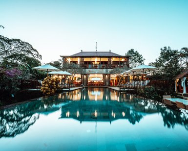 Ein luxuriöses Resort in Bali mit einem glitzernden Pool und einer eleganten Terrasse, umgeben von üppiger Vegetation.