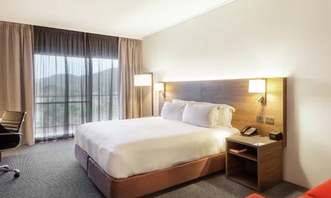 Ein stilvolles Hotelzimmer mit einem großen Bett, sanften Farben und einem Blick auf die Berge durch die großen Fenster.
