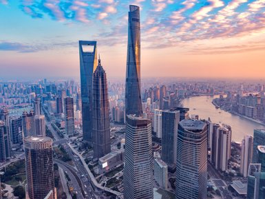 Die Skyline von Shanghai zeigt beeindruckende Wolkenkratzer, darunter den markanten Shanghai Tower, umgeben von einem sanften Sonnenuntergang.