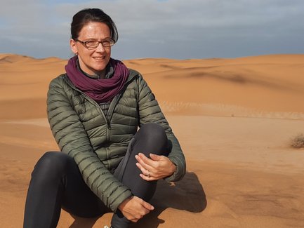 Eine Frau sitzt auf einer Düne in der Wüste - Namibia Reise mit Kindern