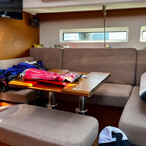 Ein gemütlicher Innenraum eines Segelbootes mit einem Tisch und gepolsterten Sitzgelegenheiten, ideal für Entspannung.