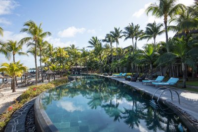 Ein luxuriöser Pool umgeben von Palmen und Liegen, ideal für Entspannung unter dem klaren Himmel von Mauritius.